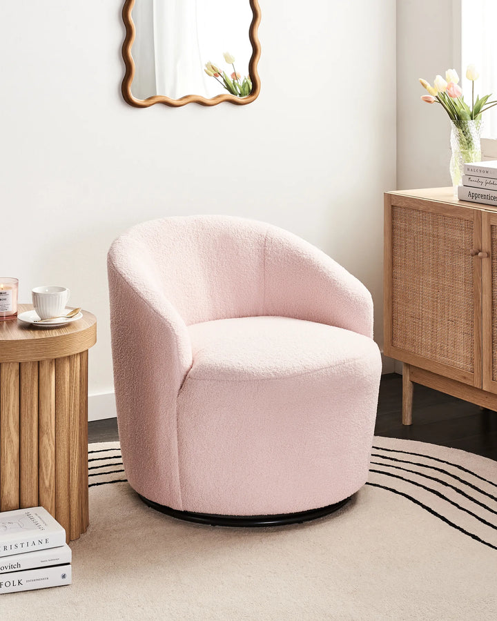 Pink armchair in a living room setting with wooden side table and cabinet.