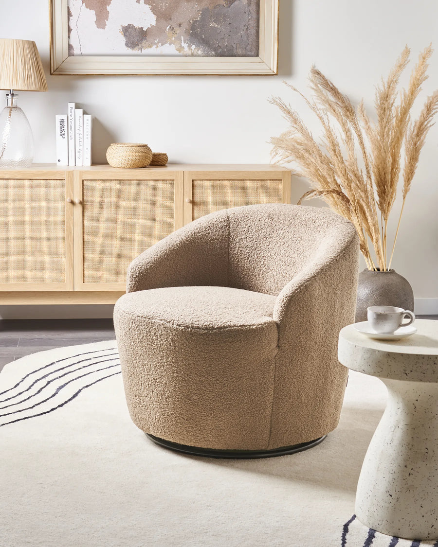 Beige armchair in a modern living room with a side table and decorative elements.