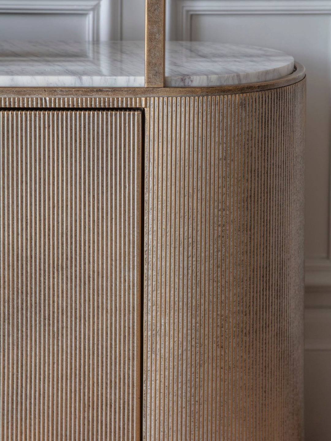 Round marble-top table with wavy wood base against a neutral wall.