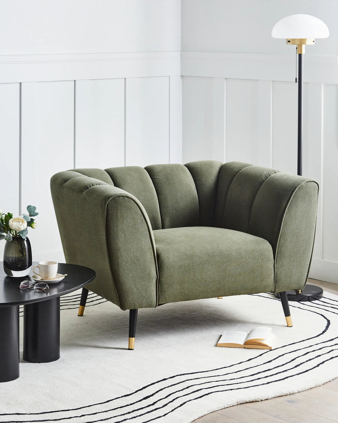 Green sofa in a modern living room with a white wall and black coffee table.