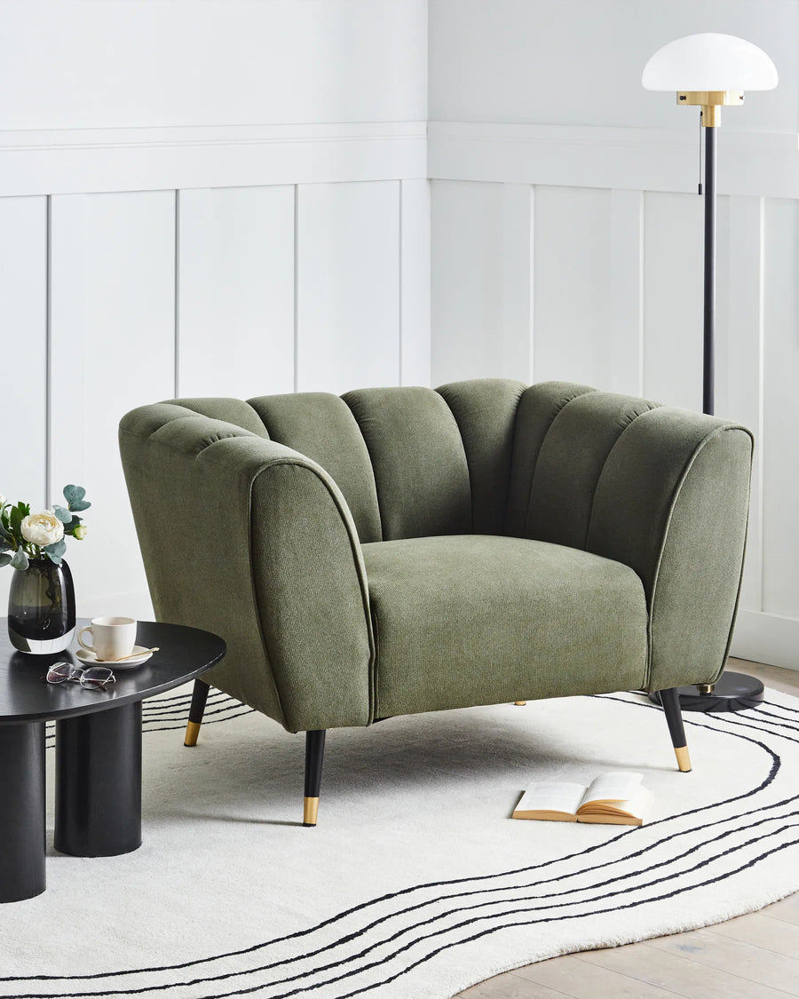 Green sofa in a modern living room with a white wall and black coffee table.