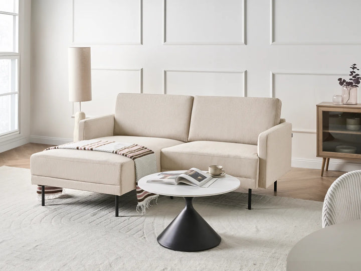 Beige sectional sofa in a modern living room with a coffee table and decorative items.