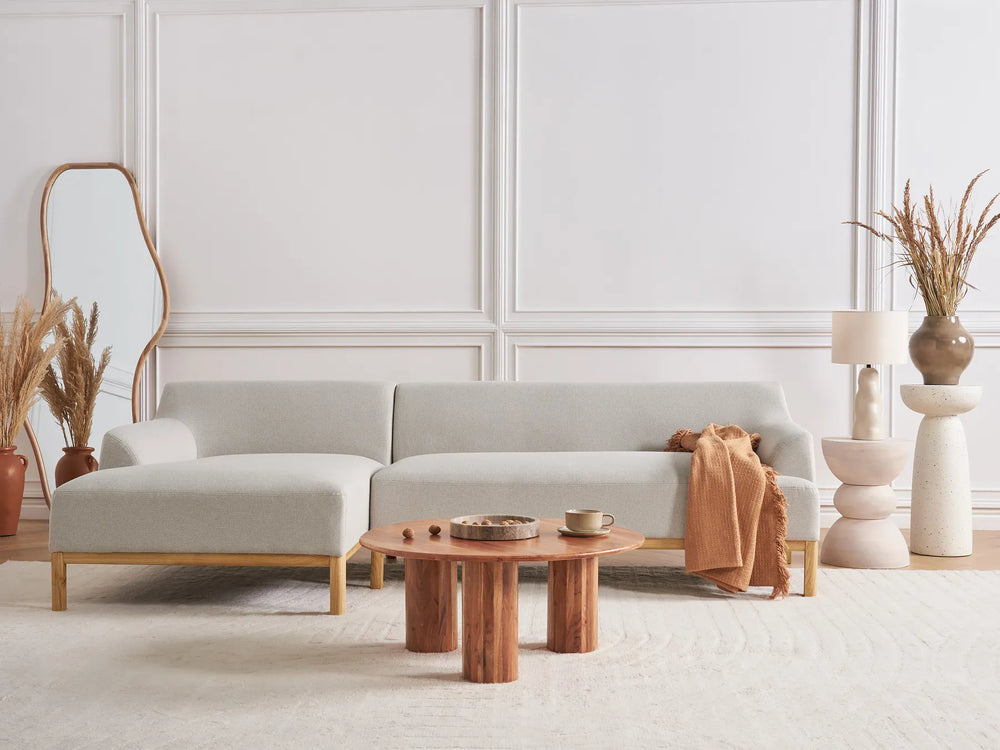 Modern living room with a light gray sofa, wooden coffee table, and decorative elements.