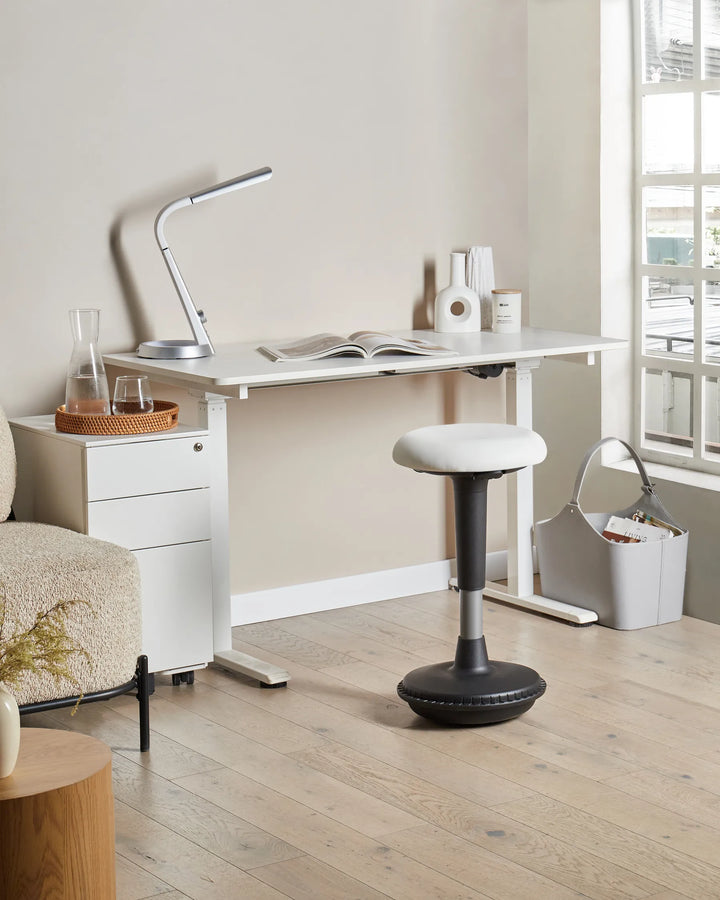 Modern office setup with a adjustable desk, lamp, and chair.