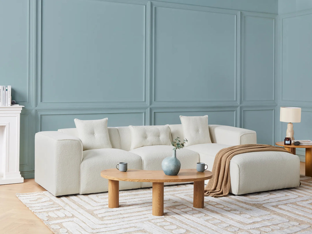 Modern living room with a white sectional sofa, wooden coffee table, and decorative items.