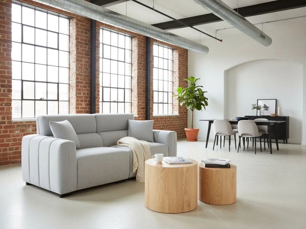 Modern living room with gray sofa, wooden coffee table, and brick wall.