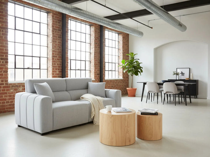Modern living room with gray sofa, wooden coffee table, and brick wall.
