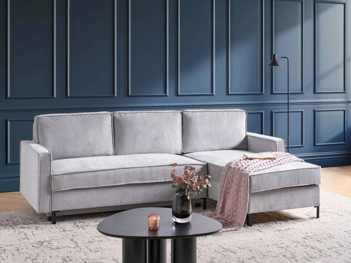 Gray sectional sofa in a room with blue paneled walls and a small round table.