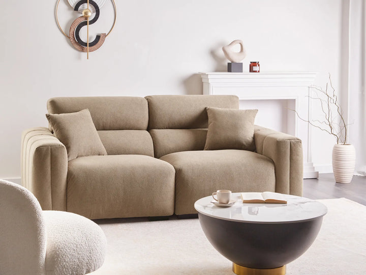 Beige sofa in a modern living room with a coffee table and decorative items.