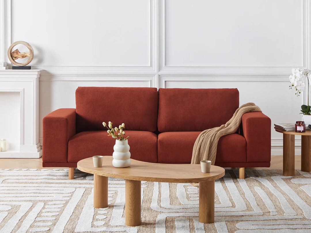 Red sofa in a living room with wooden coffee table and decorative items.