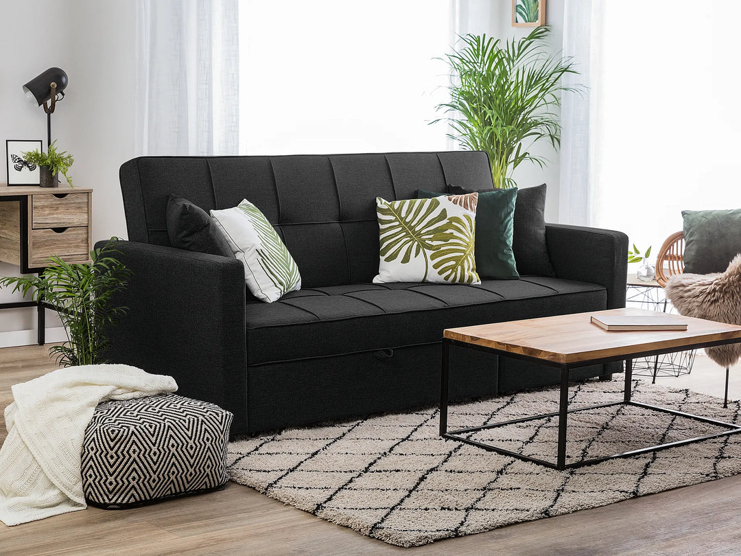 Black sofa with decorative pillows in a living room setting