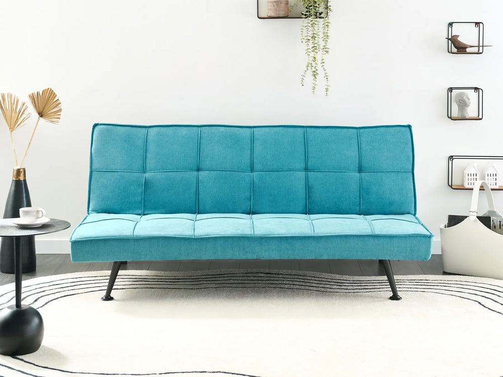 Teal futon sofa in a modern room with decor elements.