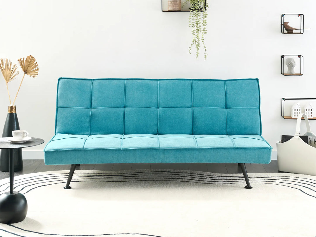 Teal futon sofa in a modern room with decor elements.