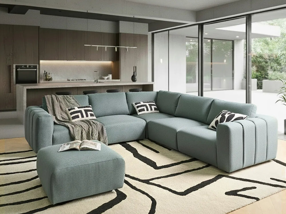 Modern living room with a gray sectional sofa, ottoman, and decorative pillows.