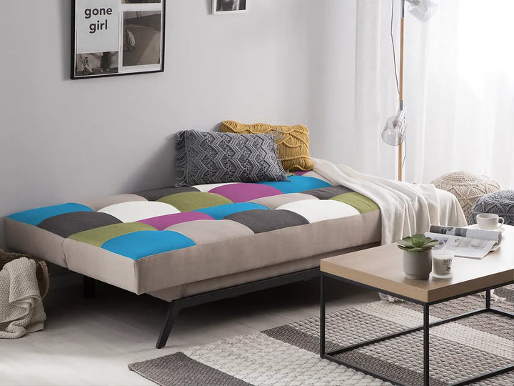 Multicolored patchwork sofa bed in a living room setting with a coffee table and decor items.