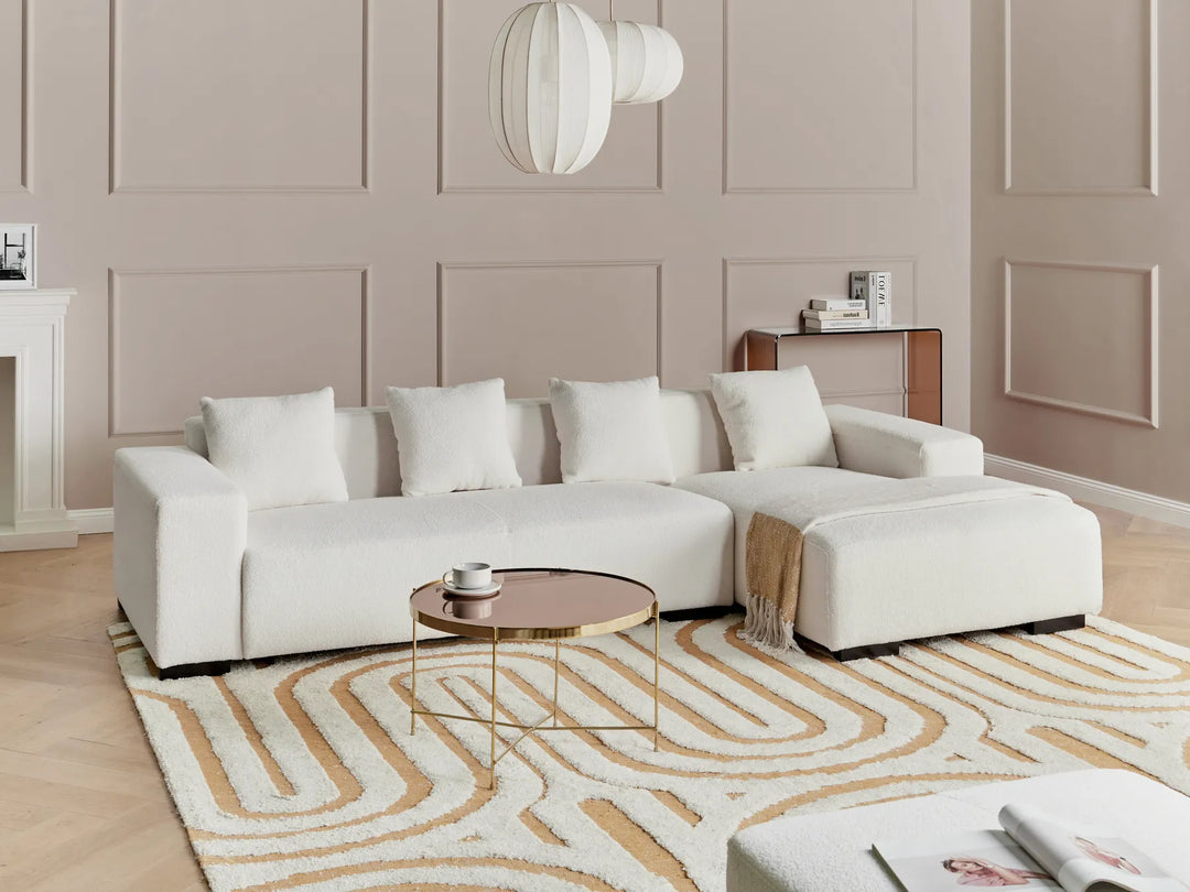 Modern living room with a white sectional sofa, coffee table, and decorative rug.