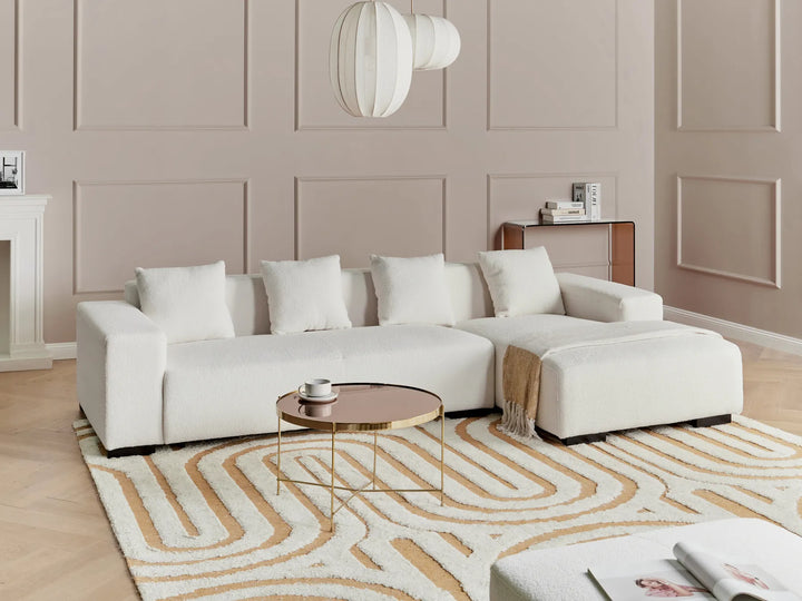 Modern living room with a white sectional sofa, coffee table, and decorative rug.
