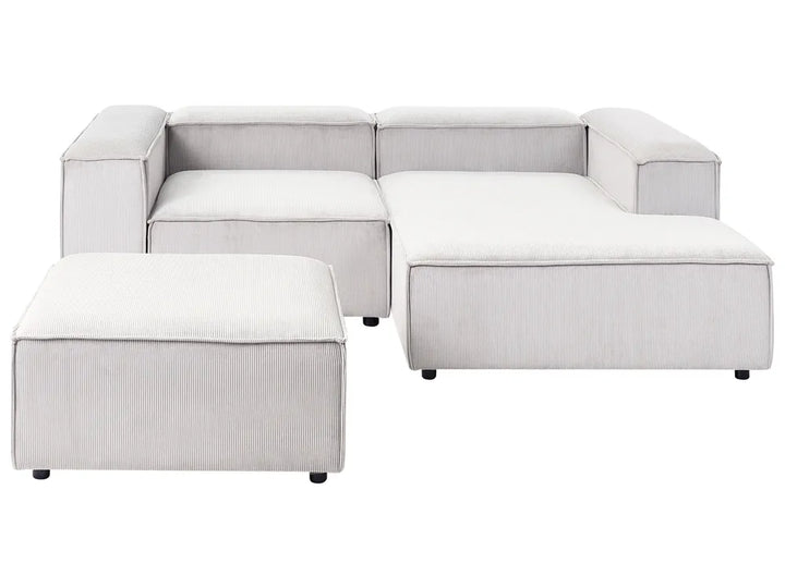 Off-white jumbo cord left-hand 3-seater modular corner sofa with ottoman in a modern living room