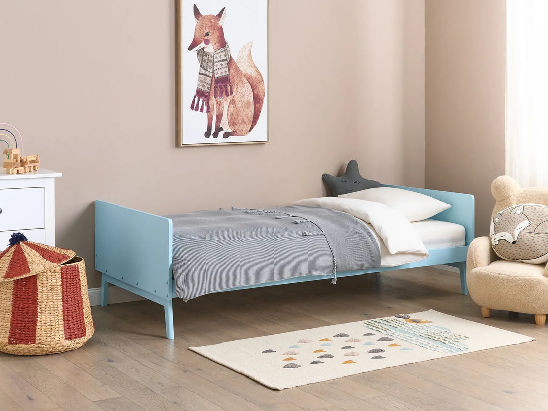 Children's bedroom with a blue bed, white nightstand, and decorative items.