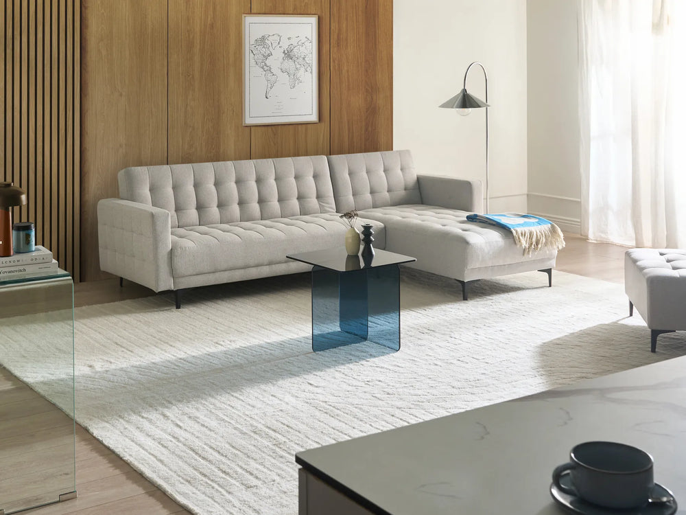 Modern living room with a gray sectional sofa, glass coffee table, and decorative elements.