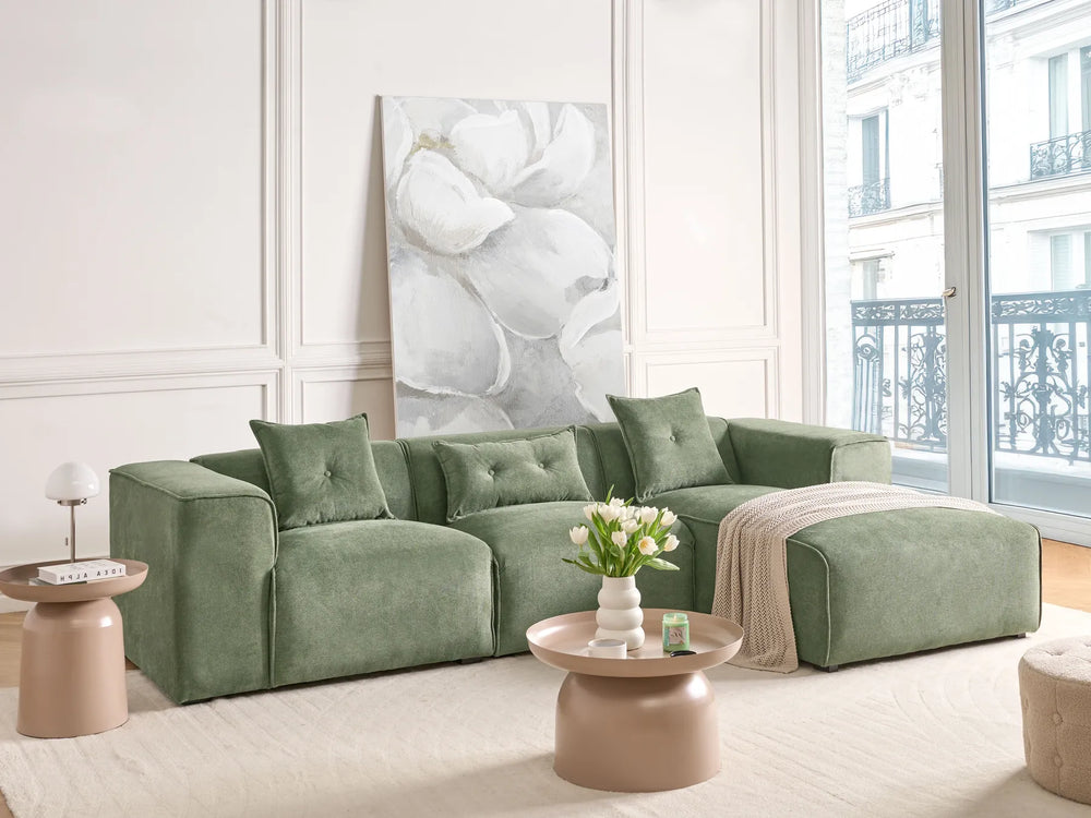 Green sofa in a living room with a large window and decorative elements.