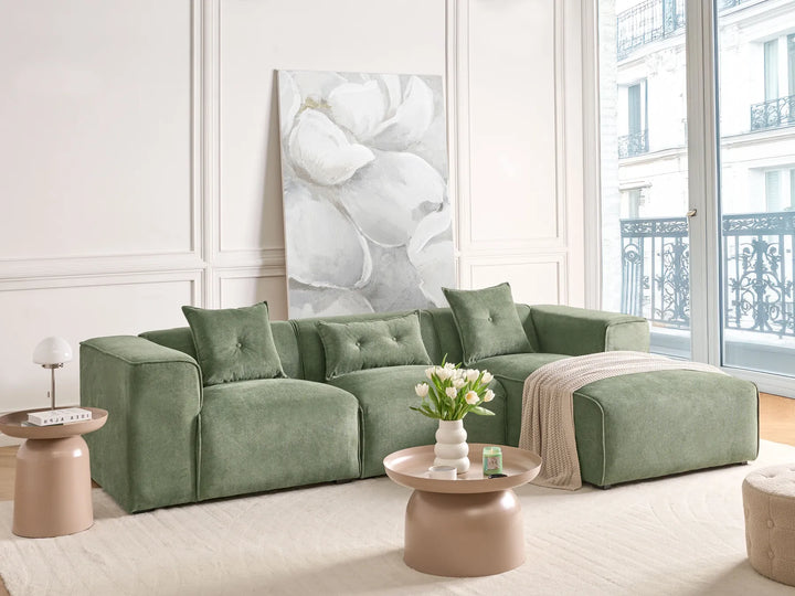 Green sofa in a living room with a large window and decorative elements.