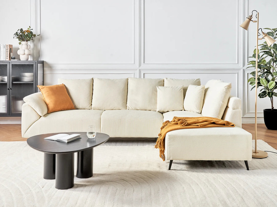 Modern living room with a white sectional sofa, coffee table, and decorative items.