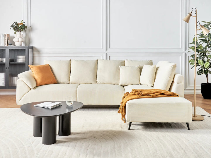 Modern living room with a white sectional sofa, coffee table, and decorative items.