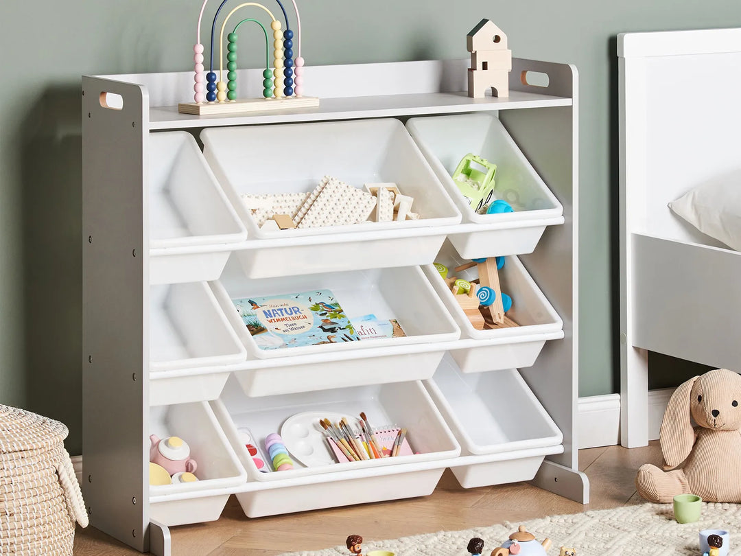 Children's storage unit with white bins filled with toys and books in a room setting.