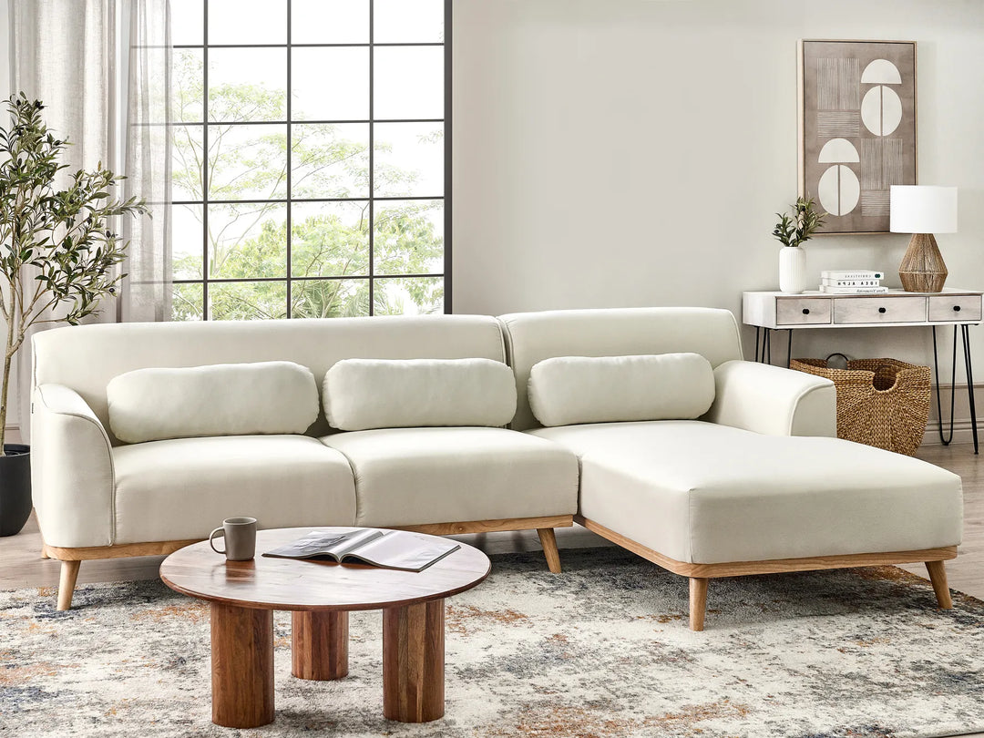 Beige sectional sofa in a living room with a wooden coffee table and decorative items.
