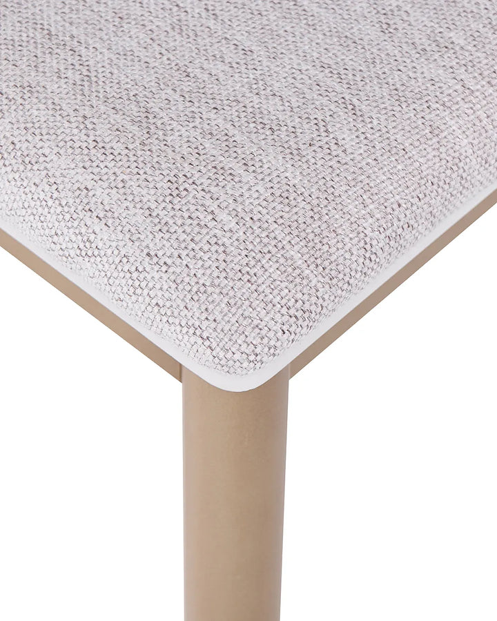 Close-up of a woven upholstered furniture seat in a light beige and white textured fabric, showing the corner meeting a light wood frame and leg on a white background.