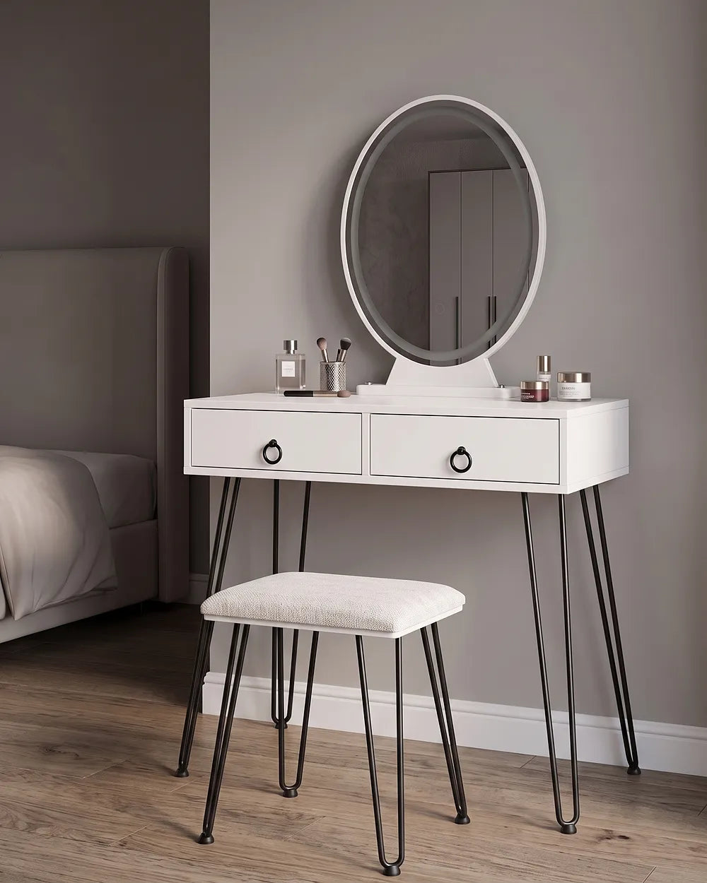 White vanity table with two drawers, black hairpin legs, and an oval mirror, shown in a bedroom setting with a matching stool.