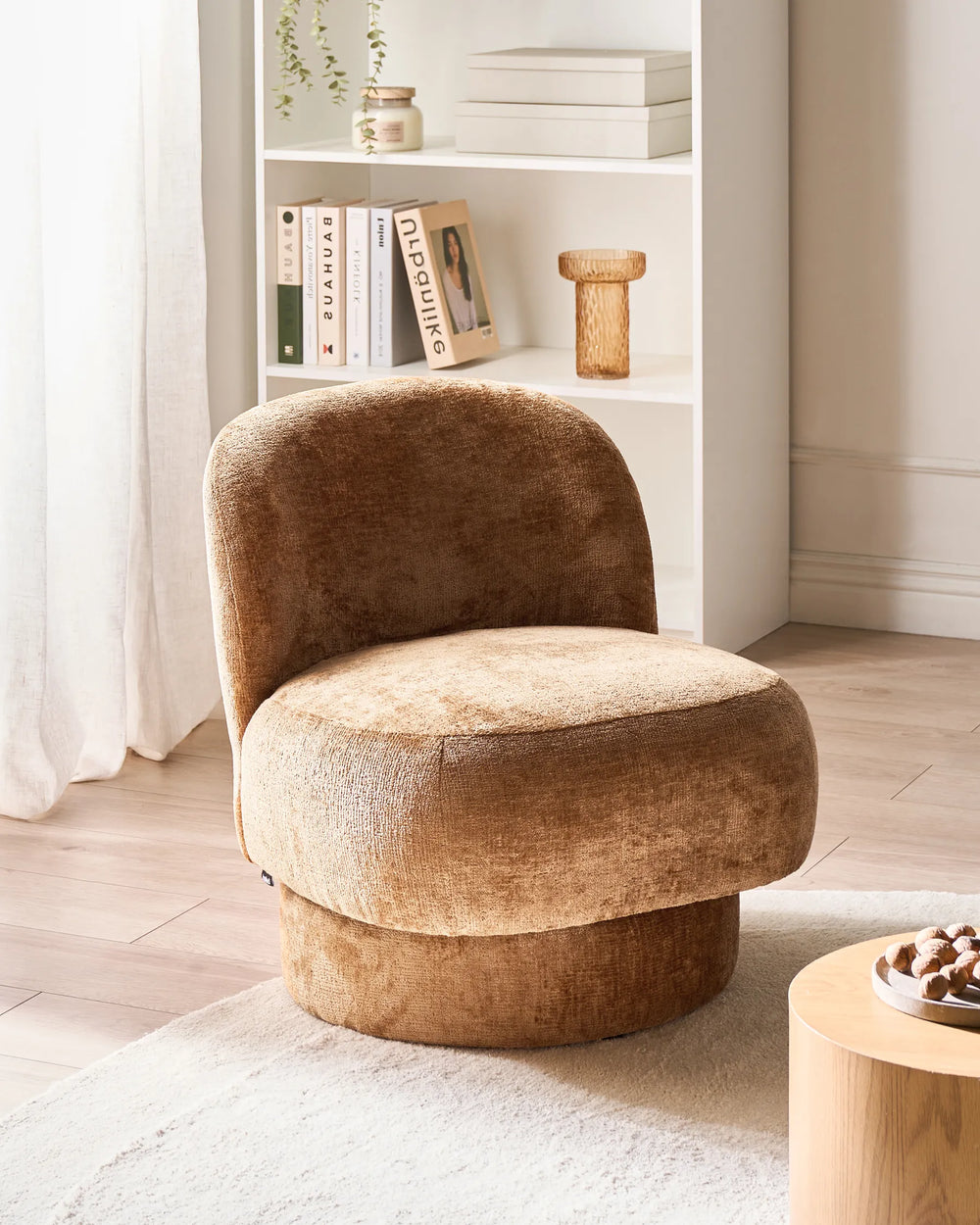 Brown upholstered chair in a room with a bookshelf and decor items.
