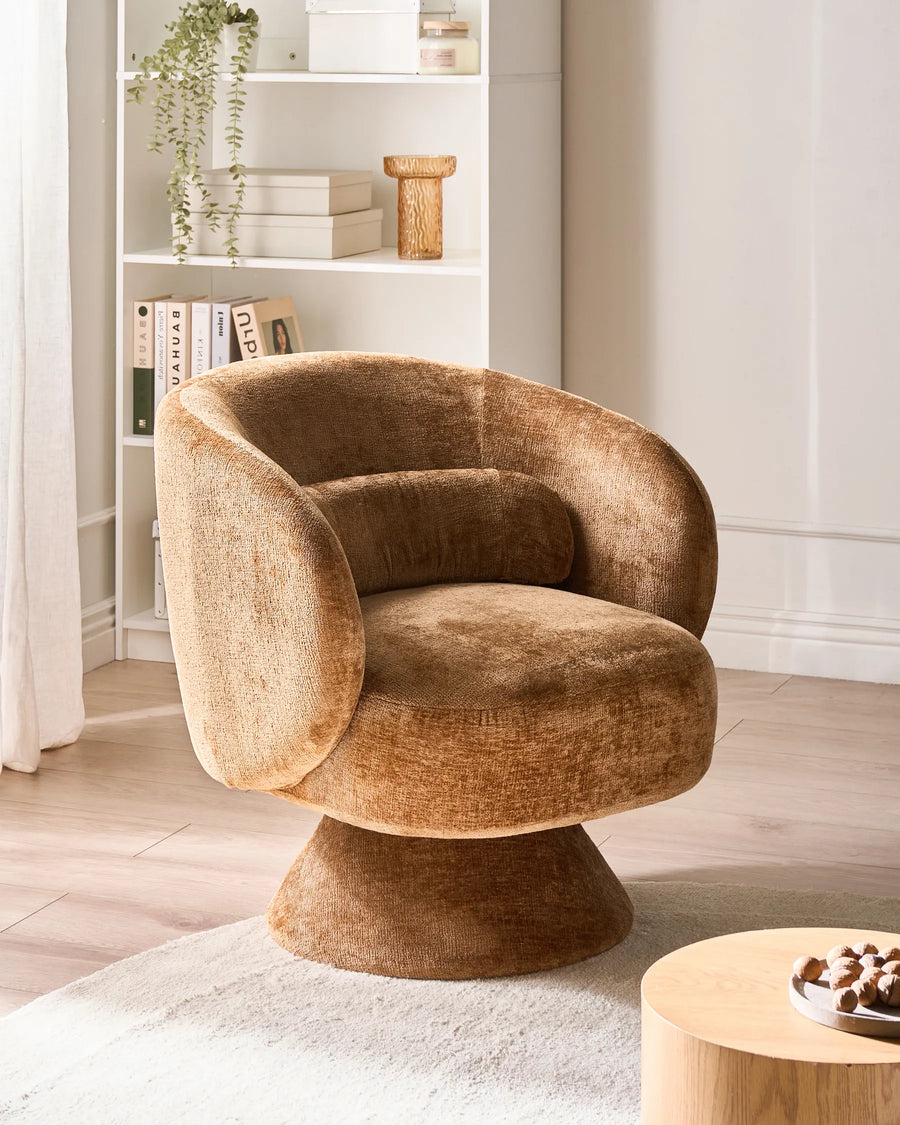 Brown textured armchair in a room with a bookshelf and small table.