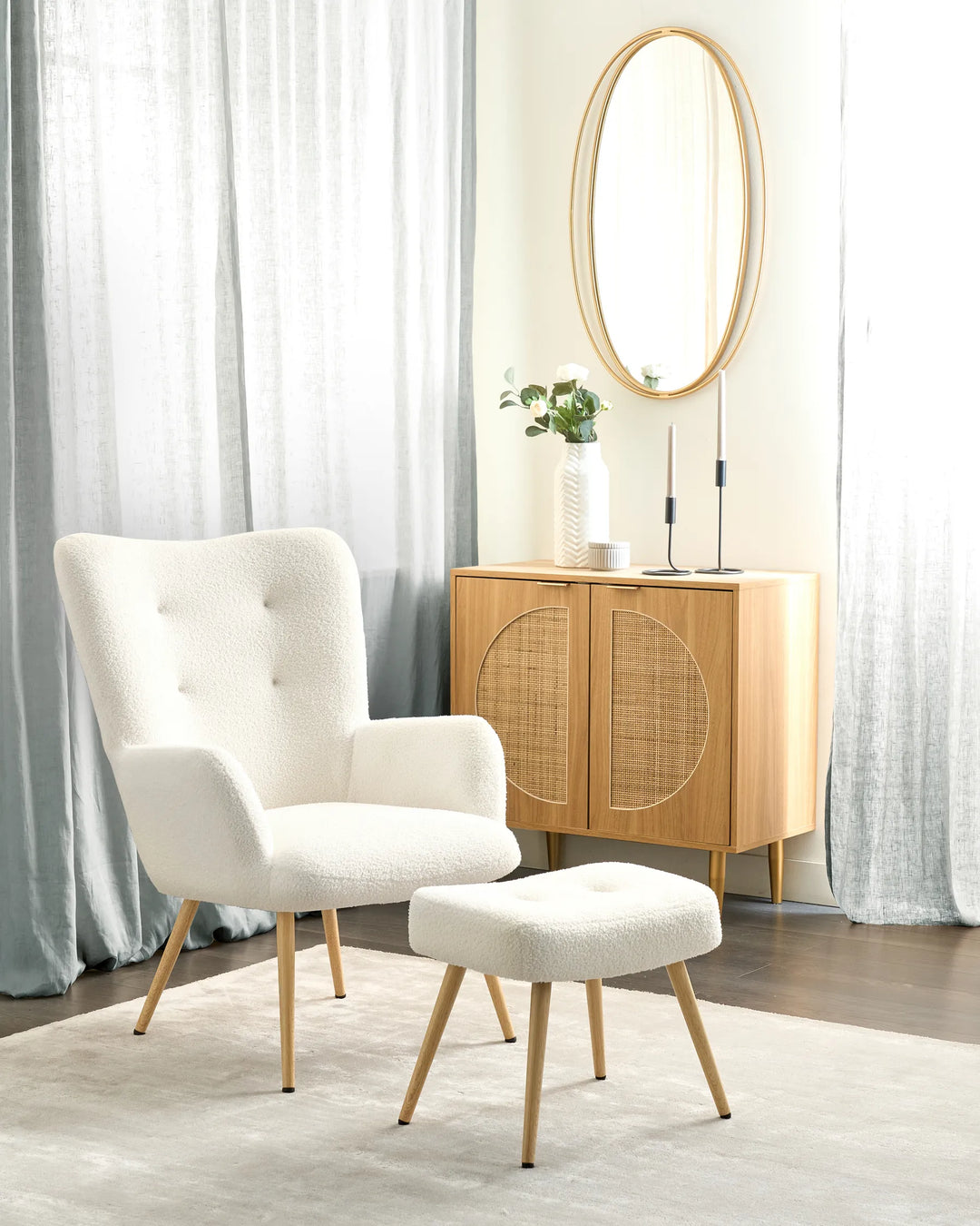 White armchair with ottoman in a room with light curtains and a wooden cabinet.