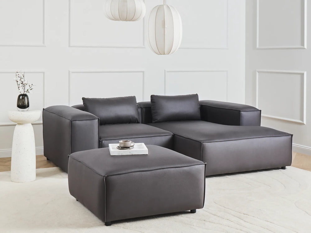 Gray sectional sofa with ottoman in a modern living room setting.
