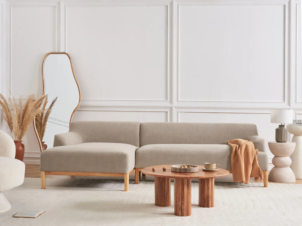 Beige sectional sofa in a modern living room with wooden coffee table and decorative elements.