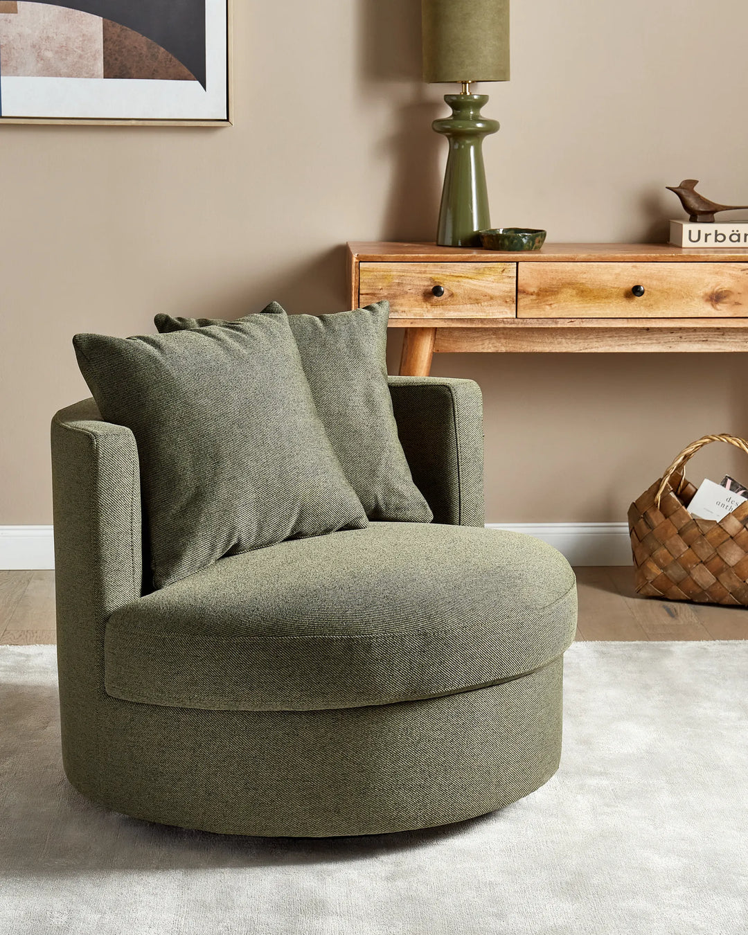 Green armchair in a living room setting with a wooden console table and lamp.
