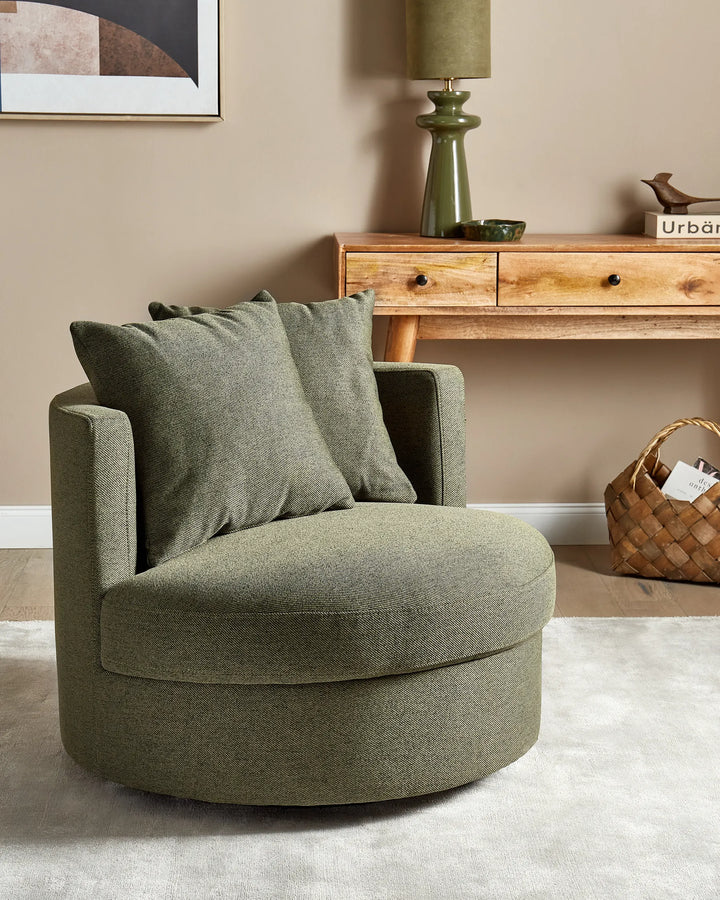Green armchair in a living room setting with a wooden console table and lamp.