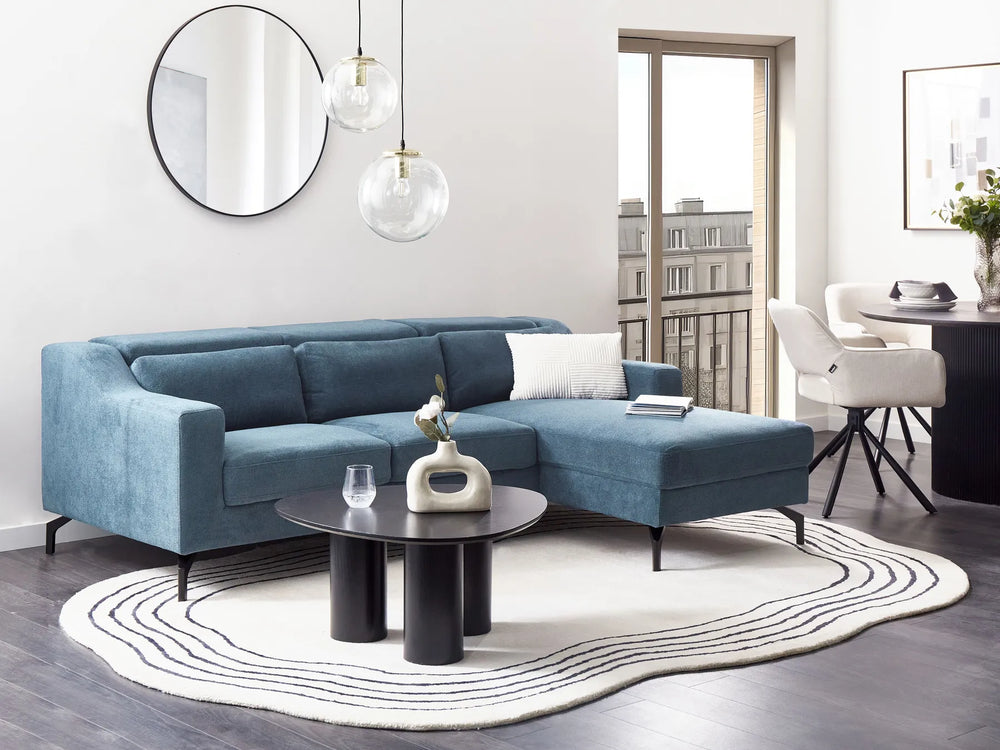 Modern living room with a blue sectional sofa, round coffee table, and decorative items.