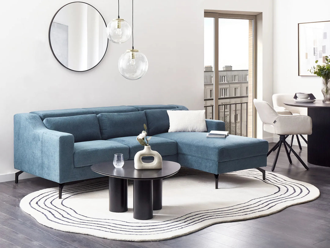 Modern living room with a blue sectional sofa, round coffee table, and decorative items.