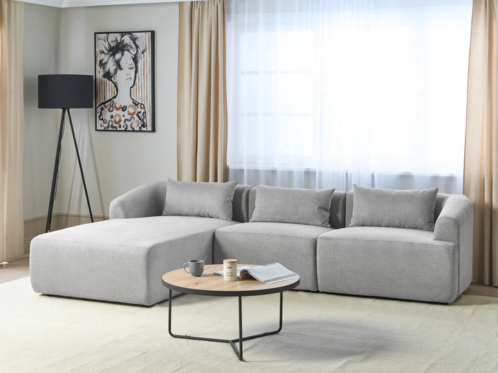 Gray sectional sofa in a living room with a coffee table and decorative items.
