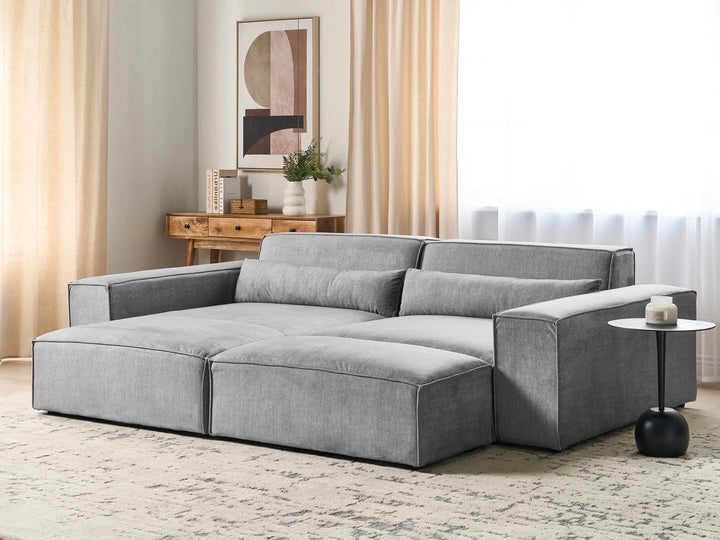 Gray sectional sofa in a living room setting with a side table and decor.