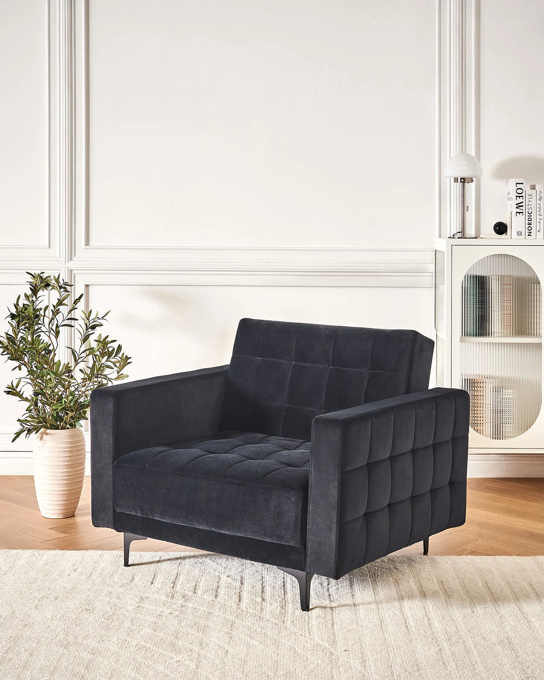 Dark gray armchair in a room with a plant and shelves.