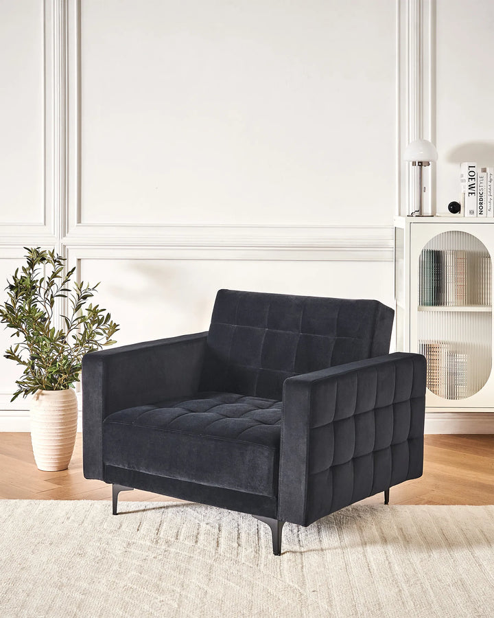 Dark gray armchair in a room with a plant and shelves.