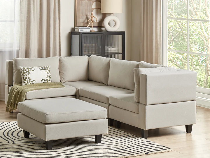 Beige sectional sofa with ottoman in a living room setting