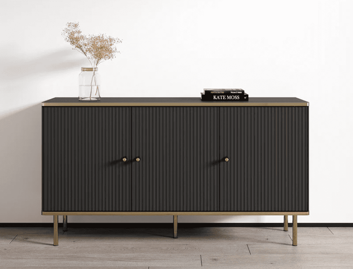 Dark wooden sideboard with gold accents on a light wood floor against a white wall.