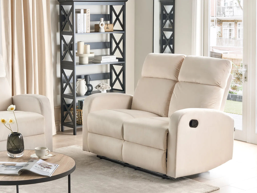 Beige recliner chair in a living room setting with a bookshelf and window.