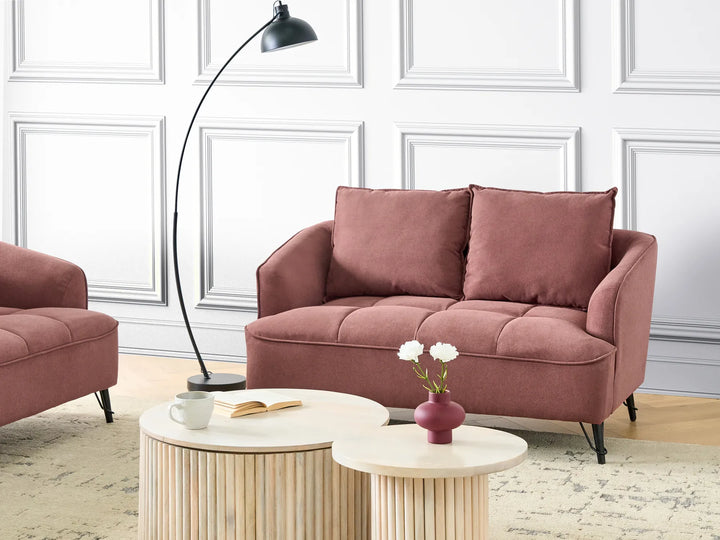 Pink sofa in a living room with a lamp and coffee table.