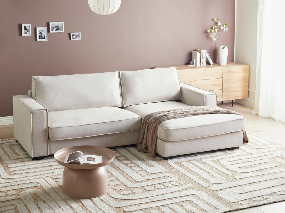 Beige sectional sofa in a living room with a coffee table and decorative items.